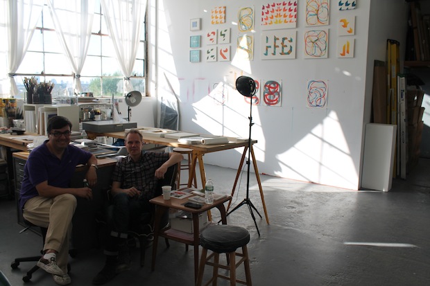 Enrico Gomez and Rob de Oude, in their studio space behind the gallery. Paintings by Enrico Gomez in the background
