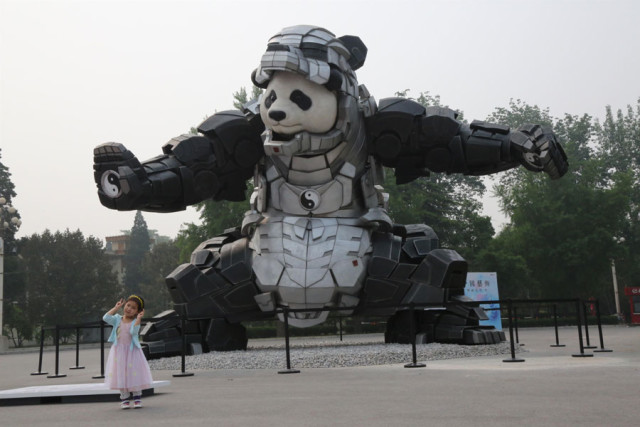 A young girl poses in front of a giant "Iron Panda" sculpture during the during the 2015 Art Beijing exhibition at the National Agriculture Exhibition 