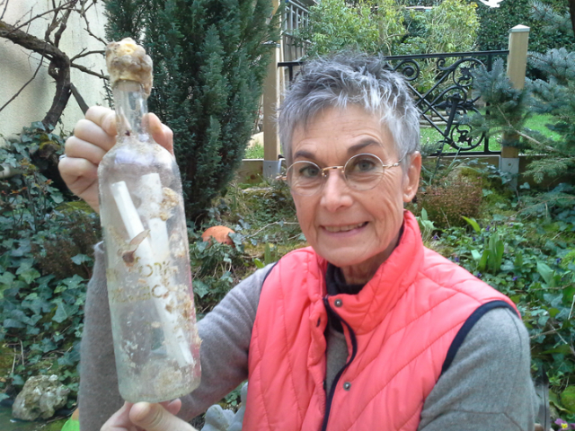 French artist Brigitte Bartholomew with the bottle containing an original drawing from George Boorujy. The bottle was recovered recovered on a beach in La Tremblade in Charente-Maritime, just north of Bordeaux. Credit: New York Pelagic